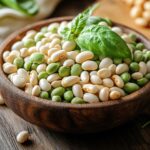 Bowl of fresh and dried lima beans on a wooden counter.