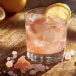 Glass of pink Himalayan salt water with lemon on a rustic table