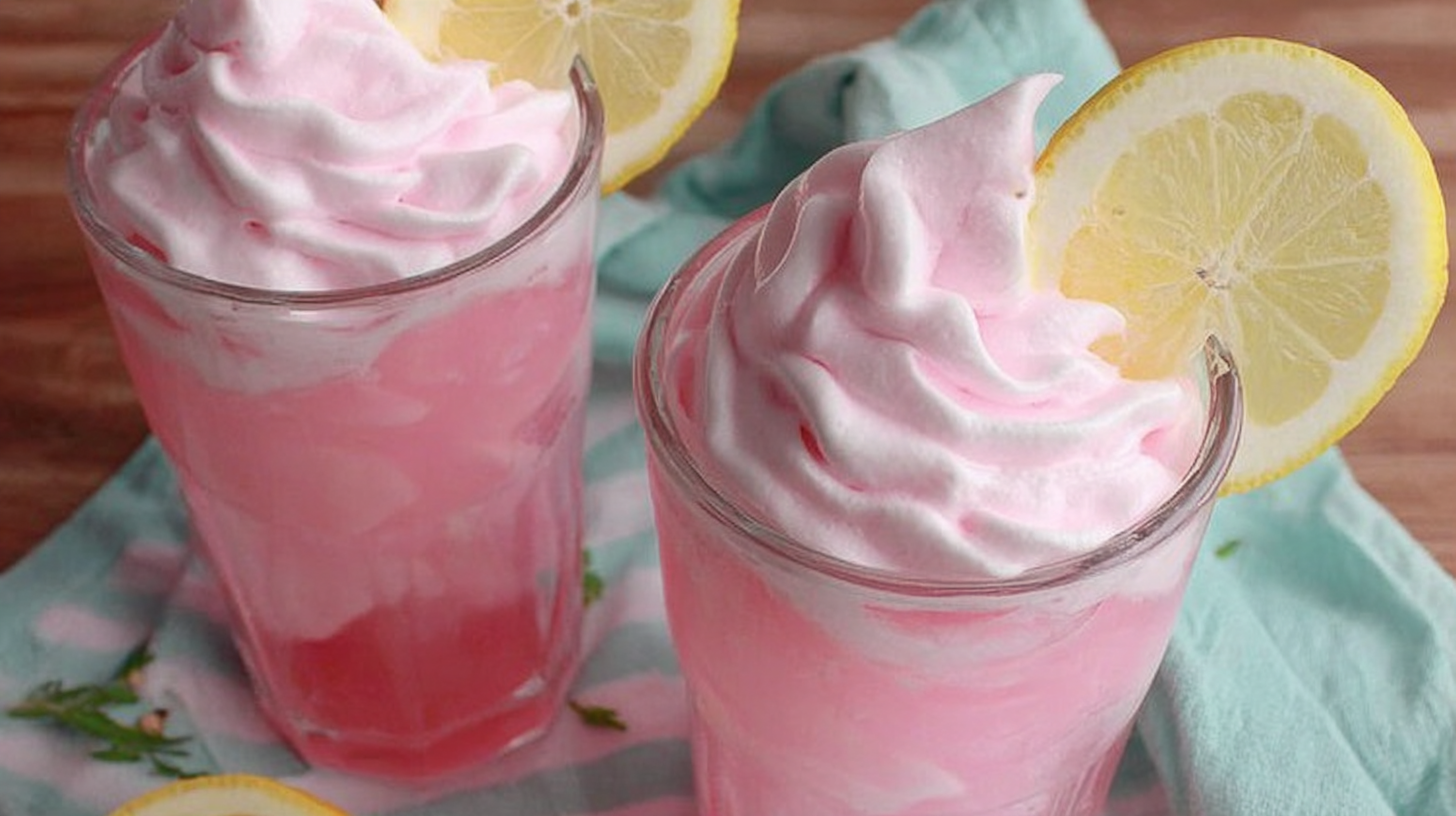 Whipped pink lemonade with cream topping in a tall glass
