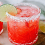 Strawberry lime mocktail margarita in a salt-rimmed glass with lime and strawberry garnish