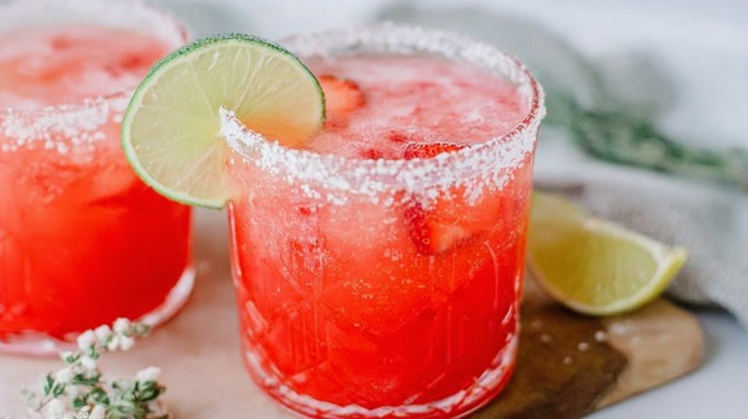 Strawberry lime mocktail margarita in a salt-rimmed glass with lime and strawberry garnish