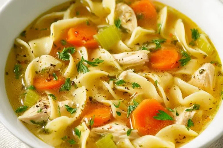 A bowl of homemade chicken noodle soup with fresh vegetables and herbs