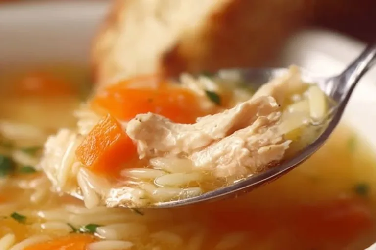 Bowl of delicious Lemon Chicken Orzo Soup garnished with herbs and lemon slices.