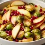 A bowl of oven roasted Brussels sprouts with apples, pecans, and pomegranate seeds