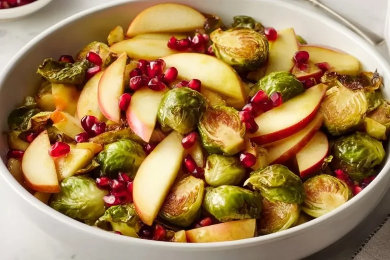A bowl of oven roasted Brussels sprouts with apples, pecans, and pomegranate seeds