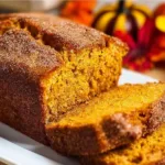 Slice of Snickerdoodle Pumpkin Bread with cinnamon on a wooden table
