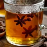 A cup of aromatic clove tea with cloves and spices on a rustic wood background.
