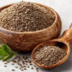 Ajwain seeds in a wooden bowl and spoon on a white background