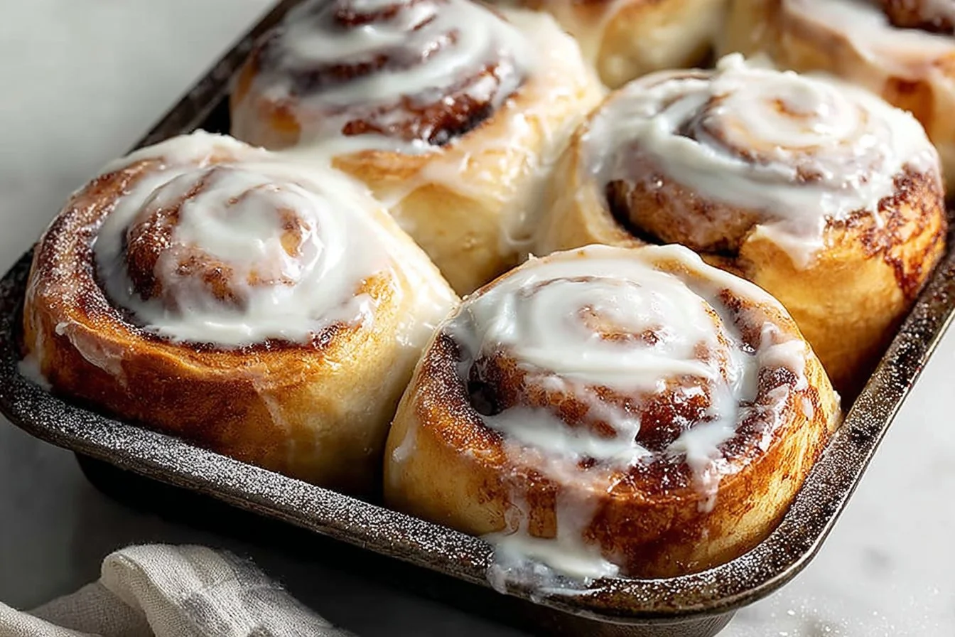 Freshly baked cinnamon roll cruffins with icing drizzled on top