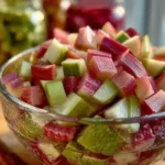 Homemade Rhubarb Cinnamon Jam in a jar with cinnamon sticks and rhubarb stalks
