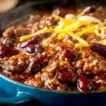A bowl of hearty chili garnished with fresh herbs and served with cornbread