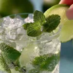 A refreshing Mojito cocktail garnished with mint leaves and lime slices.